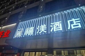 A hotel sign with illuminated Chinese characters. - XM Butler Hotel (Jinjiang)