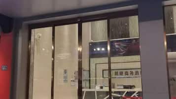 A hotel entrance with a glass door, a reception desk, and a sign with Chinese characters.