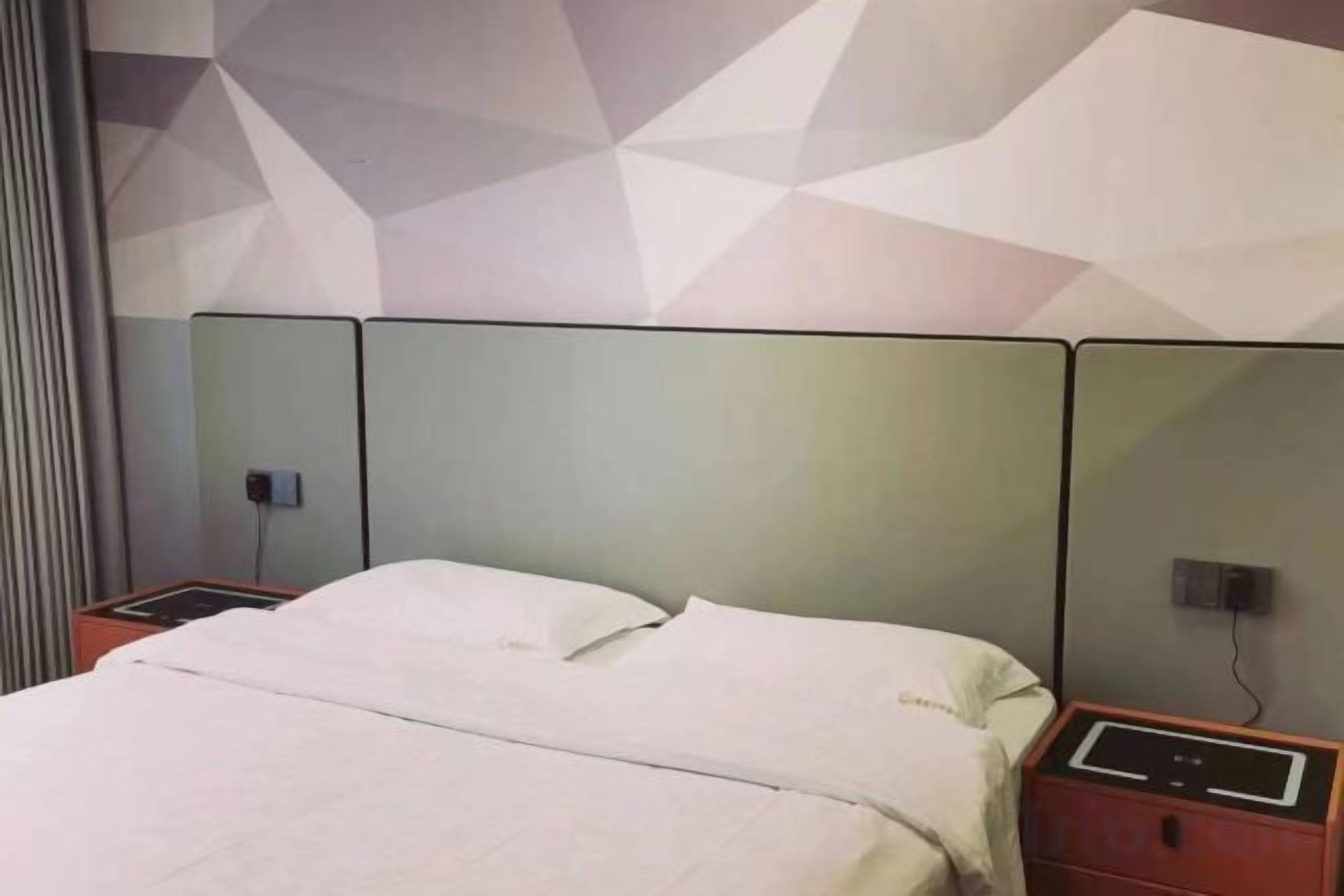 Ein Hotelzimmer mit einem Bett, Nachttischen und einer Wand mit geometrischem Muster.