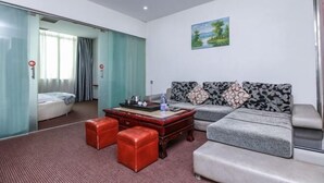 Habitación de hotel con sofá, reposapiés y cama con cortinas.