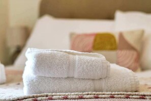 A neatly folded white towel on a bed with a patterned bedspread. - No 3 Brooklands - Central location (Filey)