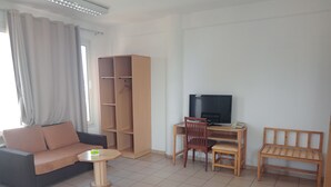 En stue med sofa, sofabord, fjernsyn, skrivebord og reol.