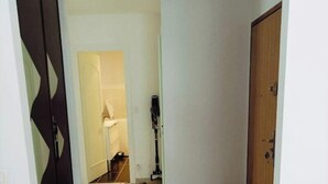 Ein Flur mit Teppich, Holztür und weißer Wand.