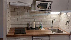 A compact kitchen with white cabinets, a microwave, a sink, and a dishwasher.
