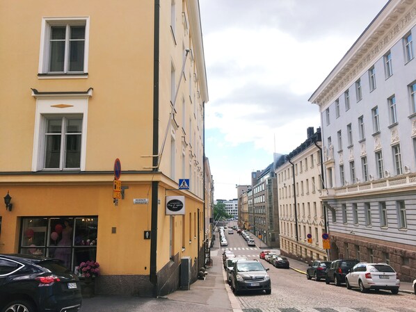 A narrow street lined with buildings, including a yellow building with a sign for a restaurant and a white building with classical architecture.