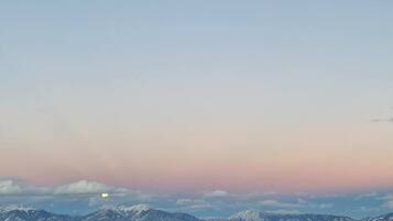 A wide-open landscape with a flat terrain and distant snow-capped mountains under a clear sky.