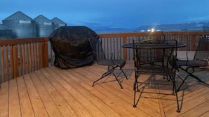 A wooden deck with a round table and chairs, a barbecue grill, and a view of mountains in the background. - Dune View -Star Gazing Getaway (Mosca)