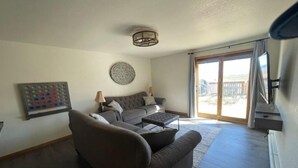 A living room with a sofa, a coffee table, a wall-mounted game board, and a ceiling light fixture. - Dune View -Star Gazing Getaway (Mosca)