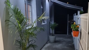 A narrow outdoor corridor with potted plants, a concrete floor, and a white fence on one side. - Peaceful apartment in the countryside (Ducos)