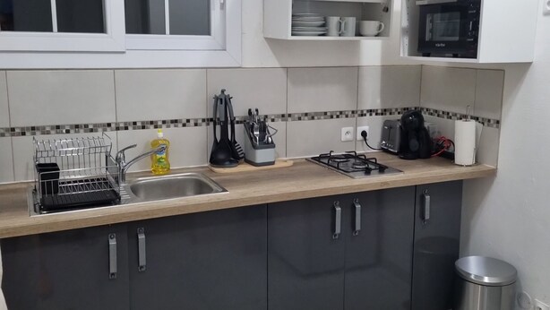 A compact kitchen with a sink, stove, microwave, and cabinets. - Peaceful apartment in the countryside (Ducos)