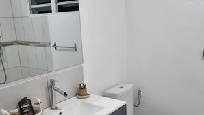 A modern bathroom with a white sink, dark vanity, and a toilet. - Peaceful apartment in the countryside (Ducos)