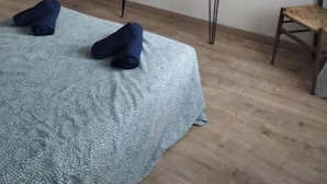A bedroom with a bed, a small table with a kettle, a chair, and a door. - 2 Bedroom Apartment in Saint-Georges-de-LuzenÃ§on (Saint-Georges-de-Luzençon)