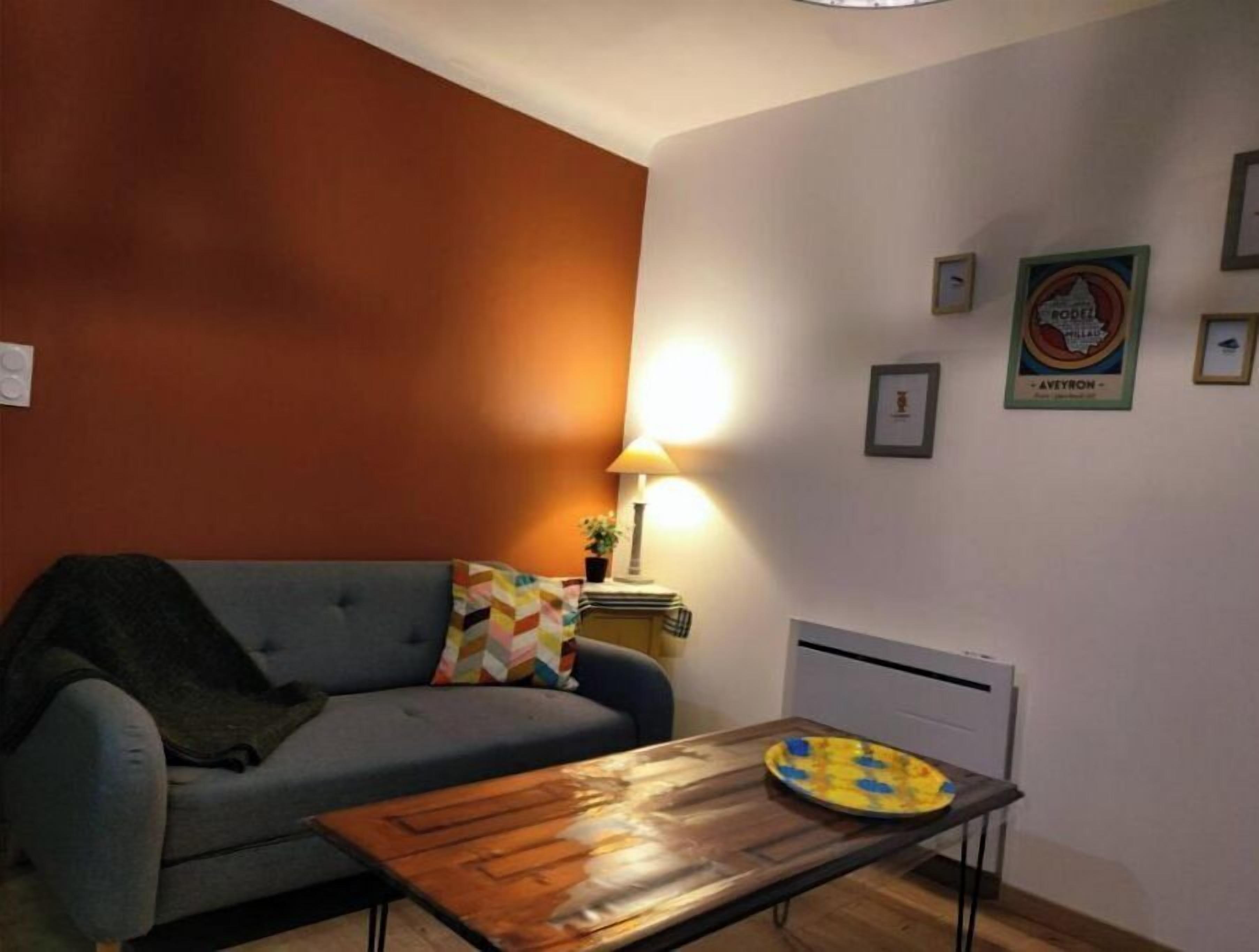 Una sala de estar con sofá, mesa de centro de madera, lámpara y radiador.
