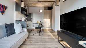 A modern living room with a grey sofa, a flat-screen TV, and a dining area with a table and chairs. - ULIV El Ángel (Mexico City)