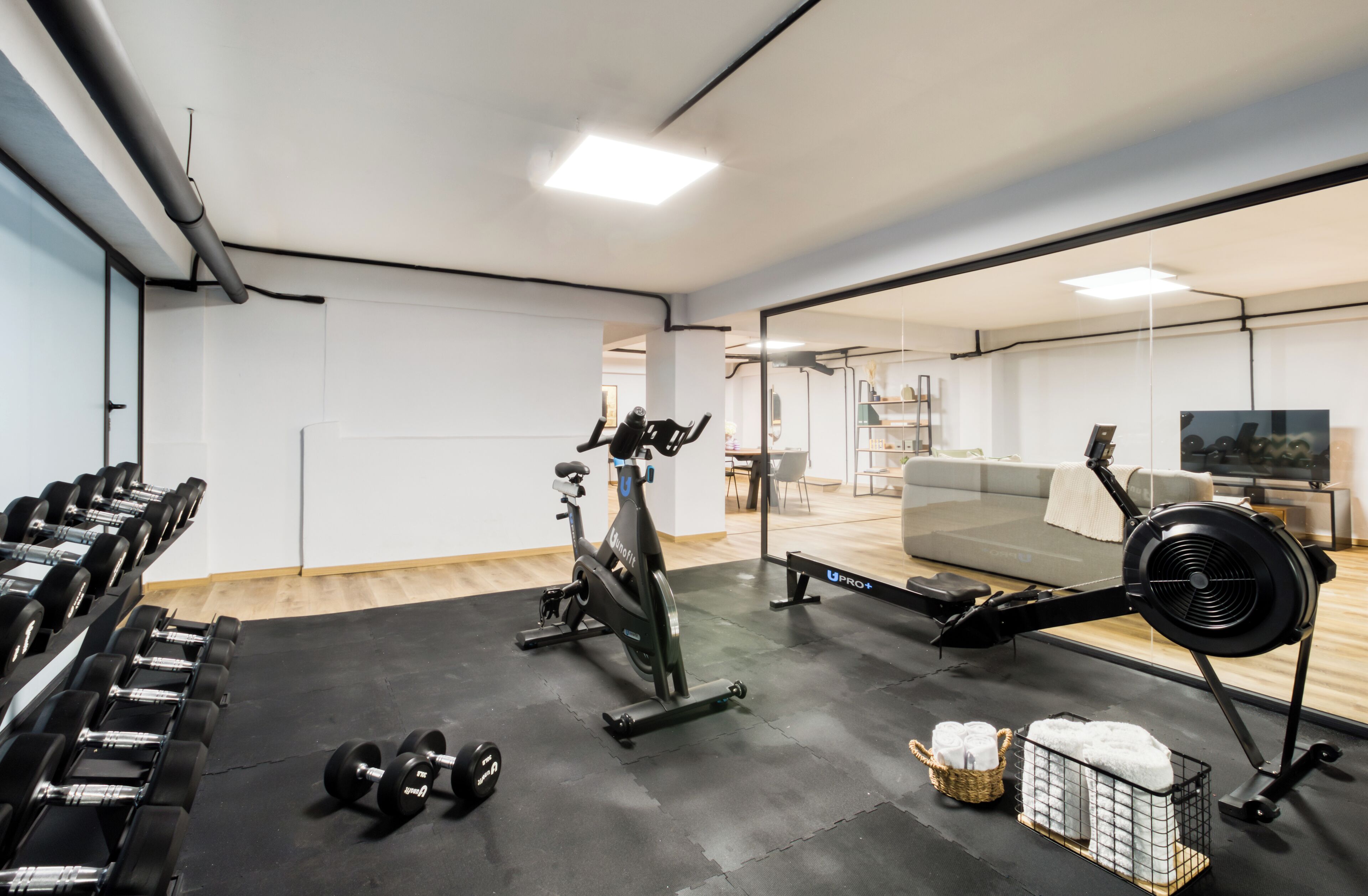 Een sportschool met trainingsapparatuur, een bank en een spiegel.