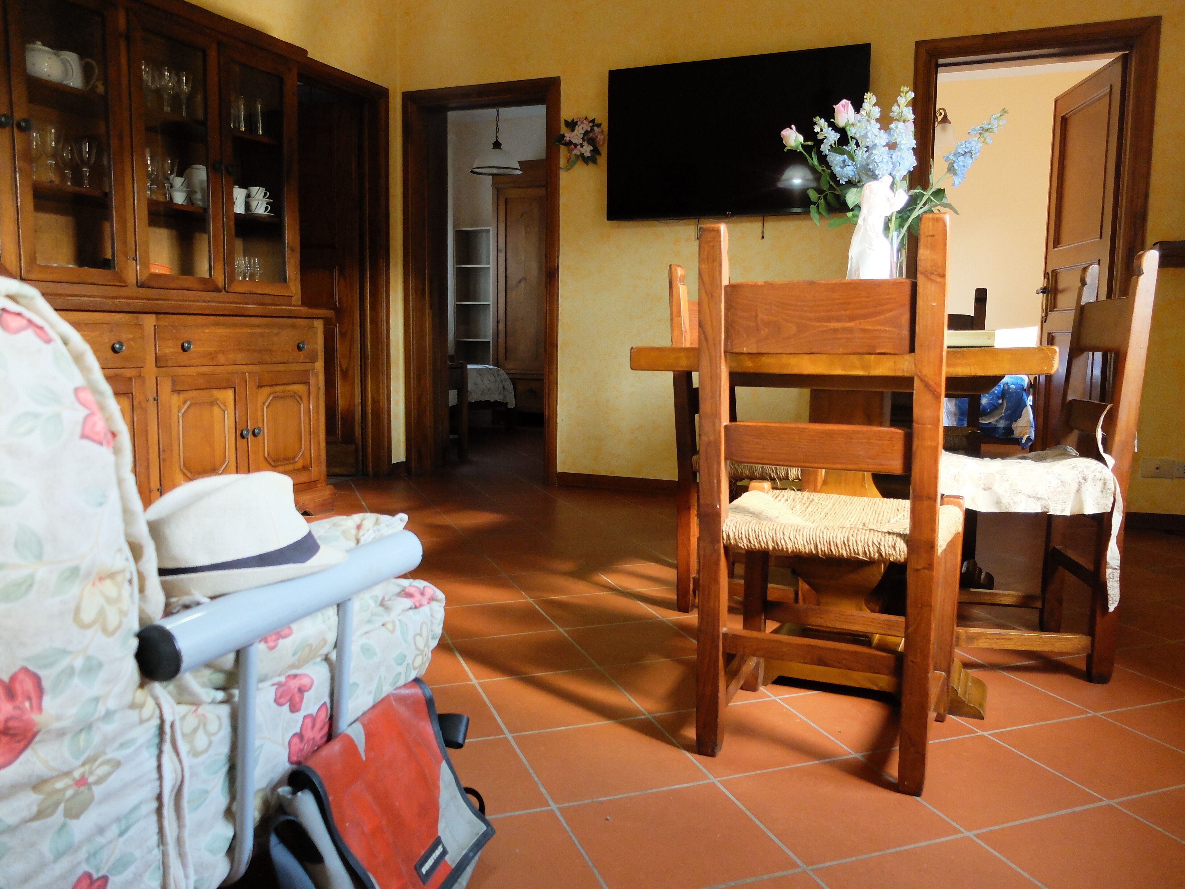 Una sala de estar con una silla de madera, un sofá, un televisor y un mueble con puertas de vidrio.