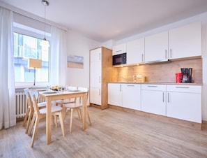 Una cocina moderna con armarios blancos, encimera de madera y un comedor con mesa y sillas.
