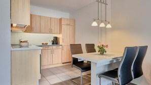 Een moderne keuken met houten kastjes, een eettafel met stoelen en hanglampen.
