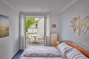 Hotellihuone, jossa on sänky, pöytä ja tuolit sekä näkymä ulos.