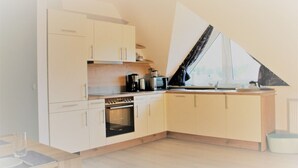 A modern kitchen with white cabinets, a built-in oven, and a window with a view. - Villa Döser Strand penthouse apartment 11 (Cuxhaven)