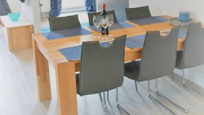 A modern dining area with a wooden table, grey chairs, and a painting on the wall. - Villa Döser Strand penthouse apartment 11 (Cuxhaven)