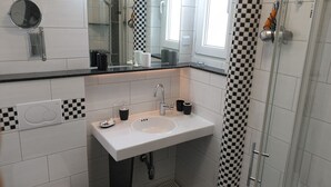 A bathroom with a white sink, a mirror, and a shower.