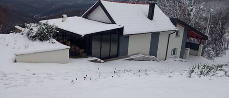 Une maison avec un toit en pente, une véranda et un garage.