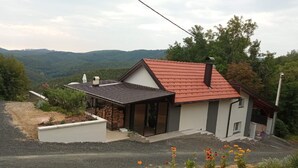 Una casa moderna con tetto rosso, un portico coperto e vista sulle colline circostanti.