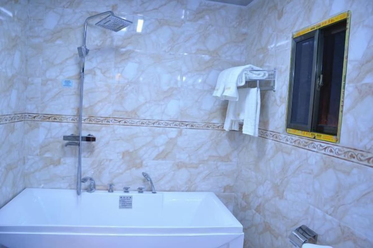 A bathroom with a marble wall, a shower, a sink, and a towel rack.