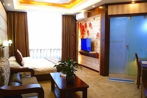 Ein Hotelzimmer mit Bett, Sofa, Couchtisch, Fernseher, Schreibtisch und einer Schiebetür.
