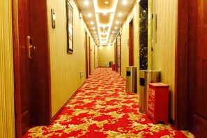 Ein Hotelgang mit rotem Teppich, Türen und einem Mülleimer.