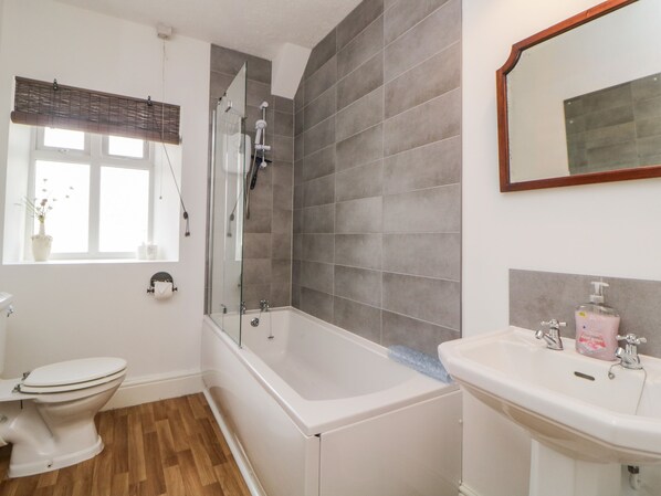 A bathroom with a bathtub, a toilet, a sink, and a window with a view of the outside. - Harmony House (Yelverton)