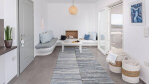 Ett modernt vardagsrum med en soffa, ett soffbord, en hängande lampa och utsikt genom en glasdörr.