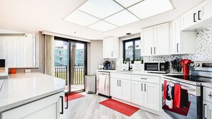 A modern kitchen with white cabinets, a microwave, and a stainless steel oven. - Beachfront 1st Floor | Heated Pool-Sherwin #107 (Daytona Beach Shores)