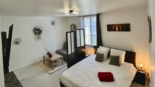 Une chambre avec un grand lit, un bureau, une chaise, une télévision et une fenêtre avec des rideaux.