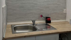 Une cuisine moderne dotée d’un évier en acier inoxydable, d’un plan de travail en bois et d’un luminaire placé au-dessus de l’évier.