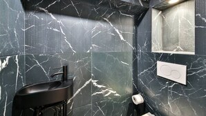 A bathroom with a black sink, marble-patterned walls, and a mirror. - 11.Flat 8 person St Lazare Galerie LaFayette 8ème (Paris)