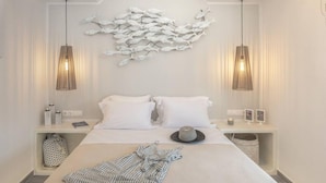 Una camera d'albergo moderna con un letto grande, due comodini, un quadro raffigurante pesci e lampade a sospensione.