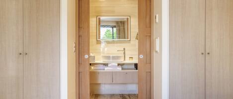 Un dormitorio moderno con un armario de madera, una cómoda empotrada con espejo y una cama con colcha amarilla.
