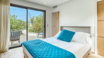 A bedroom with a bed, a chair, and a sliding glass door leading to an outdoor area.