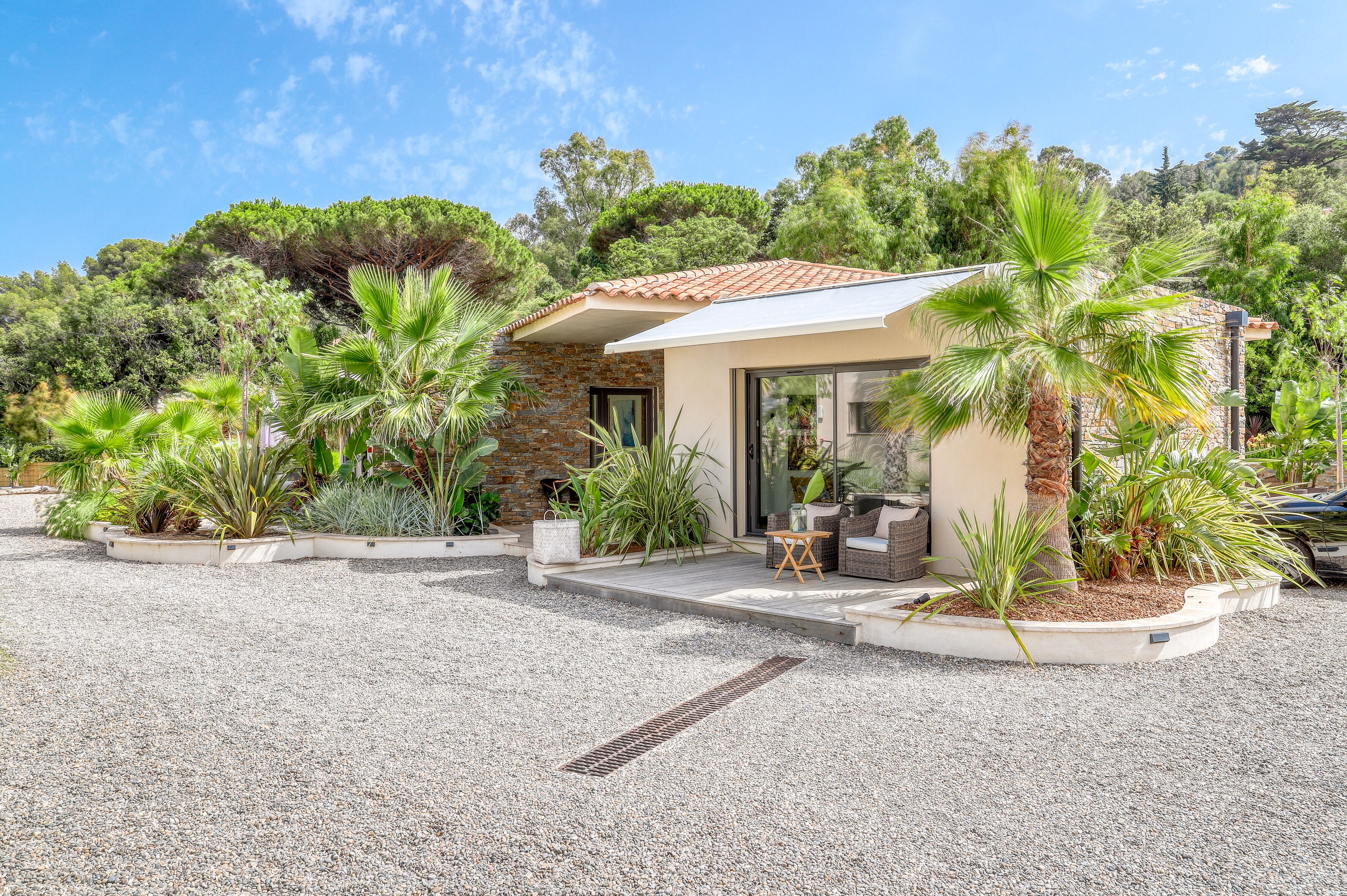 A modern house with a stone facade, a tiled roof, and a patio area with outdoor furniture.
