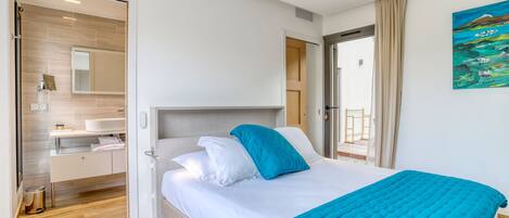 A modern hotel room with a bed, a bathroom, and a view of the outdoors.
