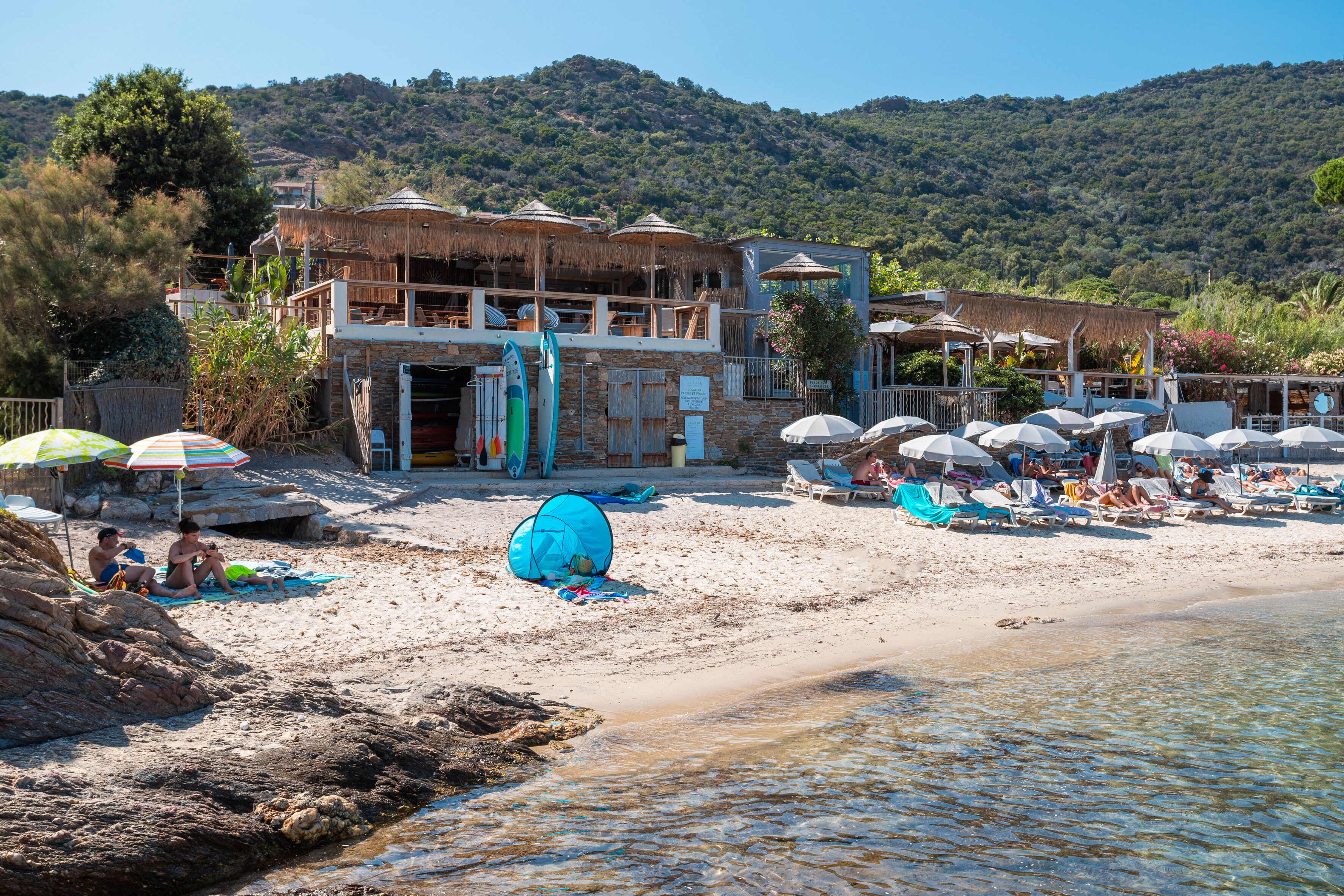 Un hôtel situé en bord de mer, doté de nombreuses chambres, d’une piscine et de parasols de plage.