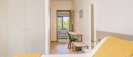 Una habitación de hotel con cama, escritorio, silla y vistas a un balcón.