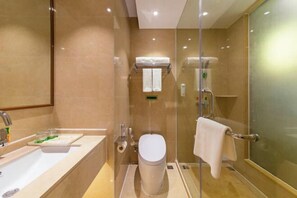 A modern bathroom with a glass-enclosed shower, a white toilet, and a sink with a mirror. - Vienna Hotel Nanning Longteng Beida (Nanning)