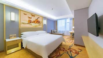 Una habitación de hotel con cama, mesita de noche, televisor y un cuadro en la pared.