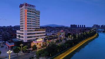 A high-rise hotel with multiple floors, a prominent entrance, and a river in the background.