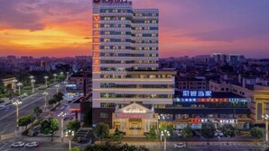 A multi-story hotel with a prominent sign on the facade, a well-lit entrance, and a parking area in front. - Vienna International Hotel （Dongguan Hengli Branch） (Dongguan)
