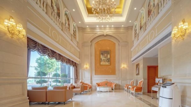 A spacious lobby with a chandelier, seating area, and artwork on the walls. - Vienna International Hotel （Dongguan Hengli Branch） (Dongguan)