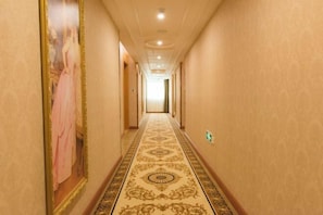 A long, narrow hallway with a patterned carpet and a large framed painting on the left wall. - Vienna International Hotel (Dongguan Hengli Branch) (Dongguan)